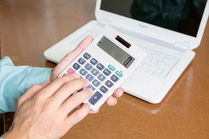 PCの前で電卓を見せる人